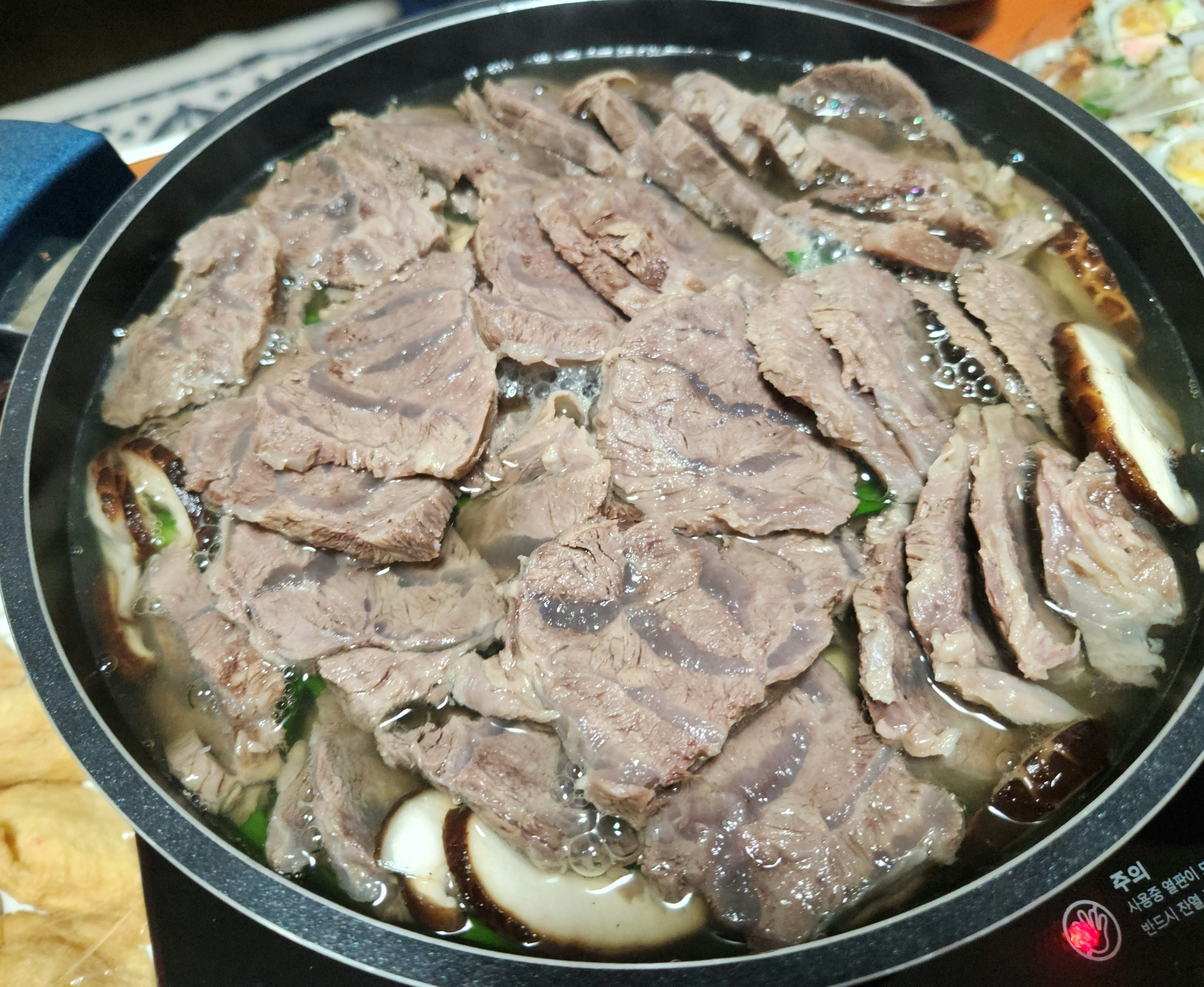 전골냄비에 끓고 있는 수육과 버섯