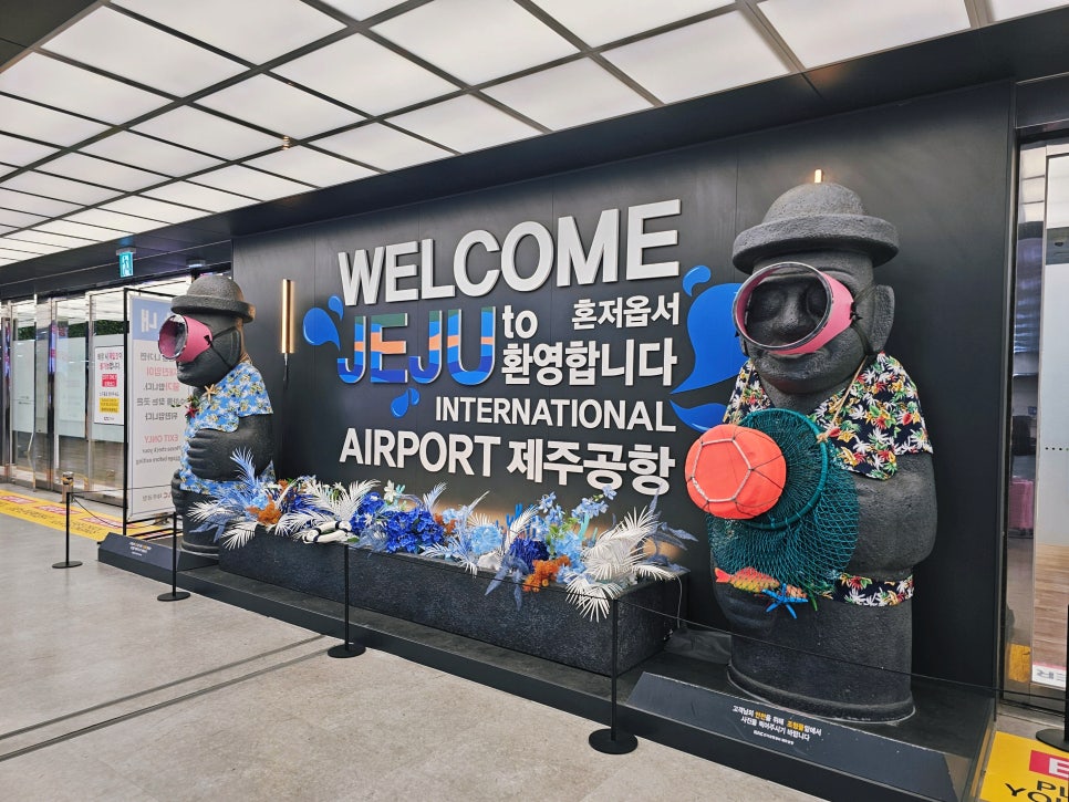 제주공항 환영 문구와 해녀 복장의 돌하르방 조형물