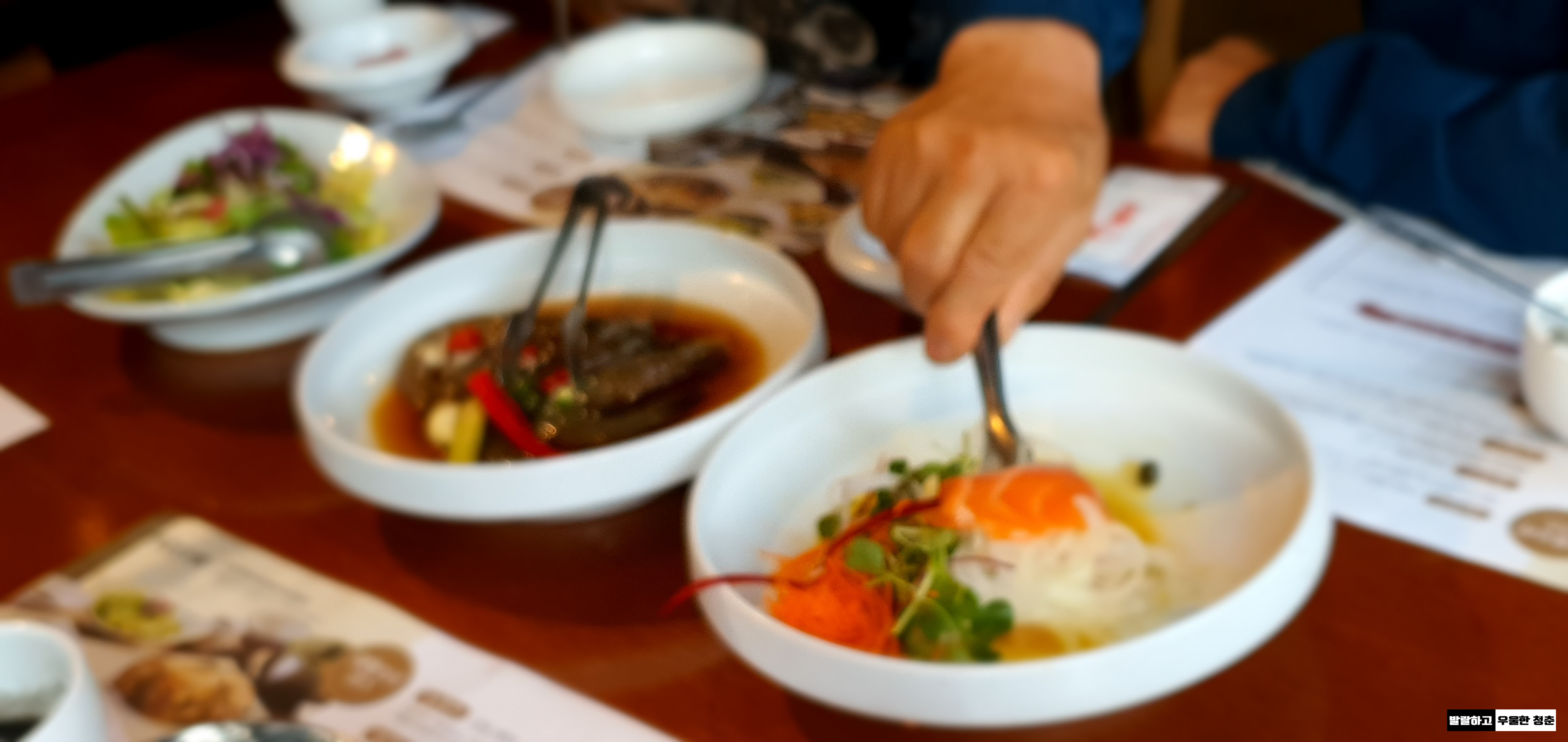 음식이 차려진 식탁과 음식을 덜어내는 사람의 손